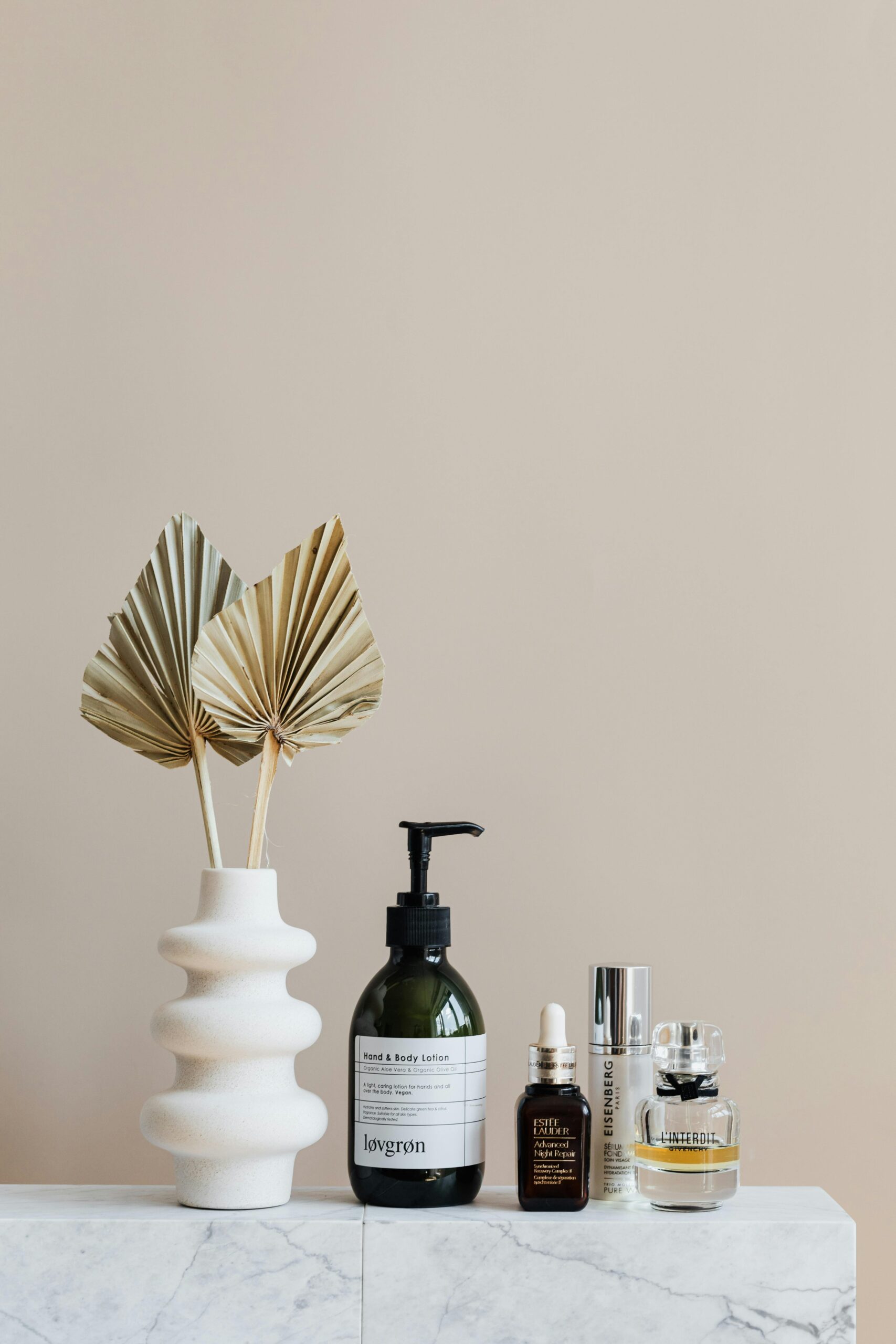 Minimalist bathroom shelf featuring skincare bottles and decorative beige vase.